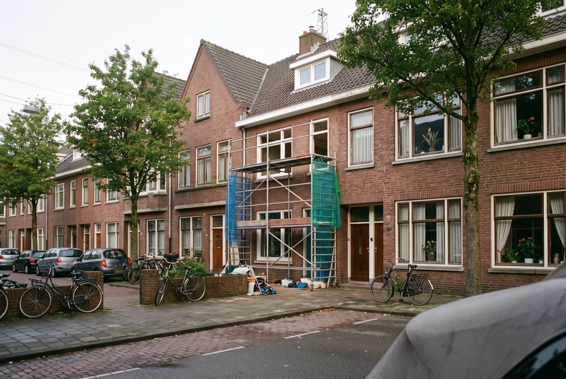 Straat met rijtjeshuizen, met een steiger voor een woning die wordt verbouwd